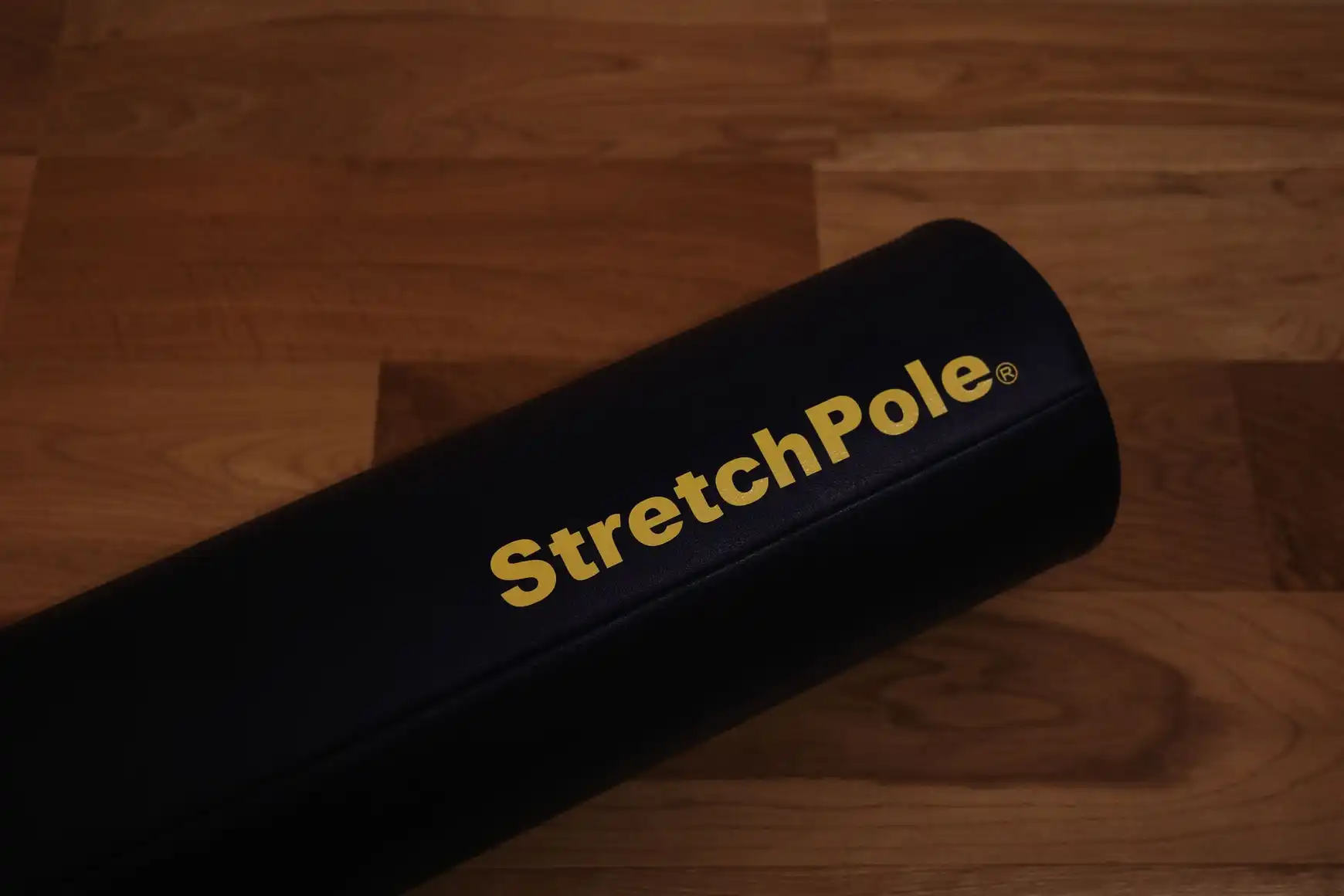 フローリングに置いたストレッチポールEX(ネイビー)の端。金色のStretchPoleロゴが見える
